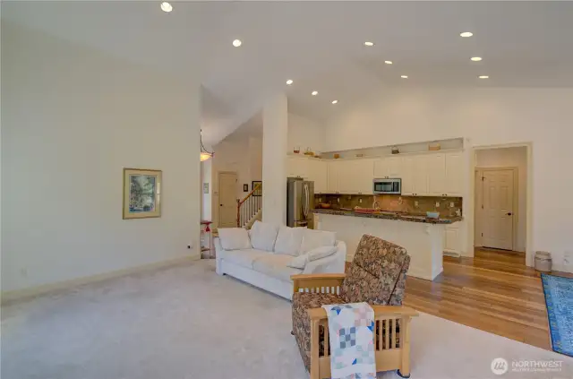 From the living room looking towards the main entrance, stairway to the second floor bedrooms, kitchen, laundry room and primary suite.