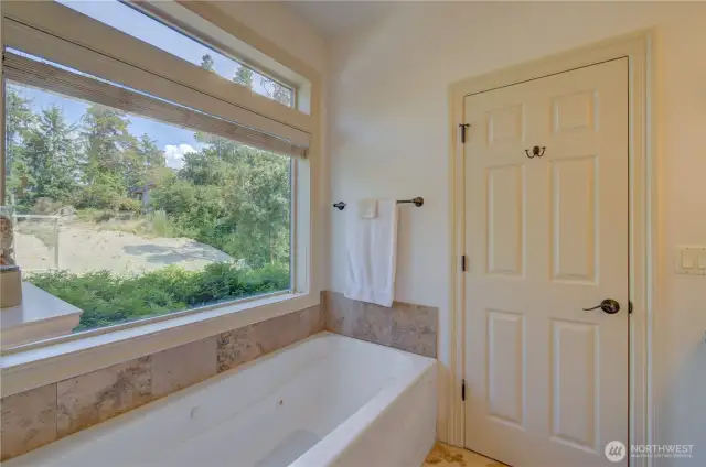 Primary suite full bath including jetted tub and shower. The doorway goes to the primary bedroom