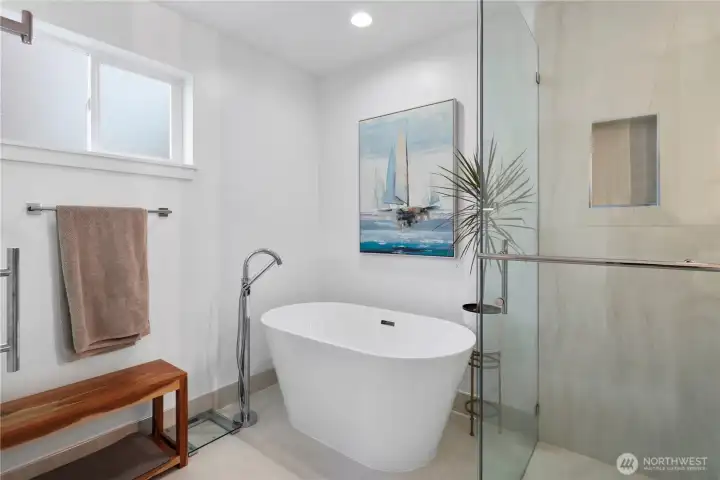 Tiled shower, tiled floors w/ floor backsplash, full height glass surround, freestanding bathtub w/ freestanding faucet, new vanity, quartz counter w/ waterfall, double faucets & sinks, lighted & heated mirror