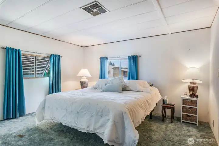 Spacious primary suite with soothing colors and large windows creates a peaceful retreat at day’s end.