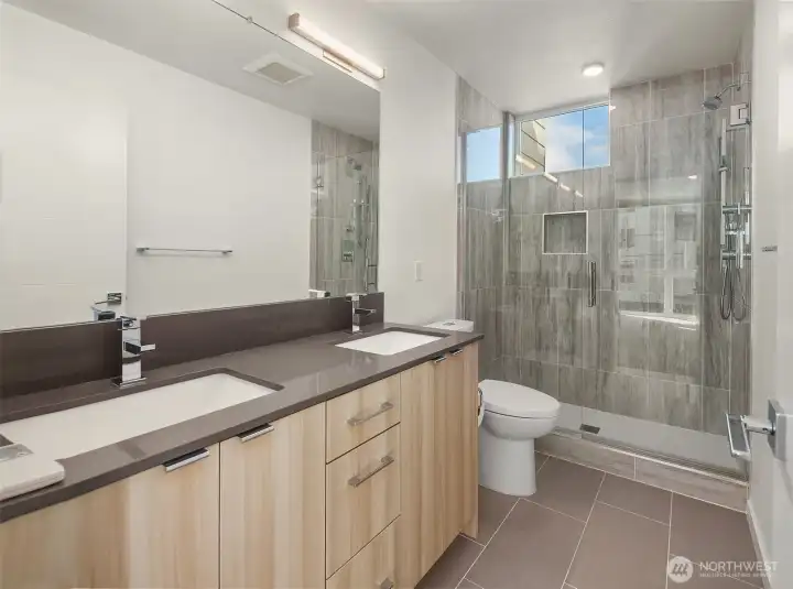 Primary ensuite bathroom with double vanity and floor-to-ceiling tile shower.