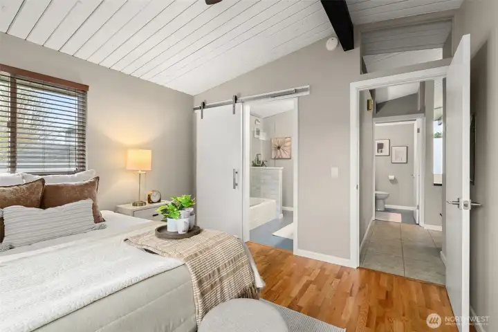 Through the doorway at left is primary full bath, with walk-in closet beyond. Down the hall you can see the guest powder room.