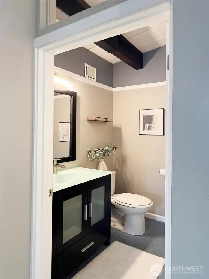 Even the stylish guest powder bath has vaults & beams - and when you tour, don't miss the transom window above the door! Updated glass-top vanity and marmoleum floors here.