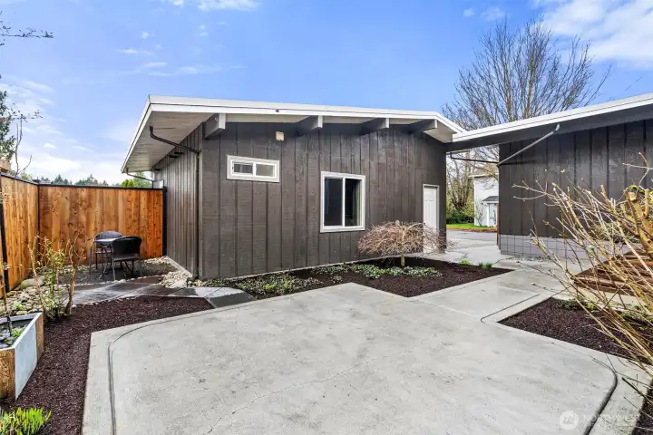 Isn't this a pretty place for quiet thoughts - or summer BBQs. At one time, there was a hot tub to the left of the garage/ADU, where you see the table and chairs now. White door leads into finished garage storage with loft above. Windows at center and left are part of the ADU.