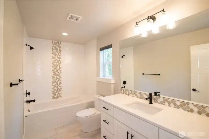 Upstairs second bath features quartz counters, tile and abundant light!