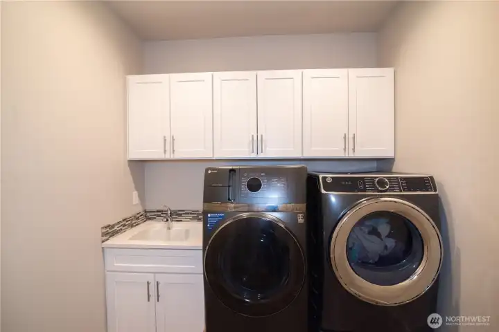Downstairs laundry room with a sink and built in storage.