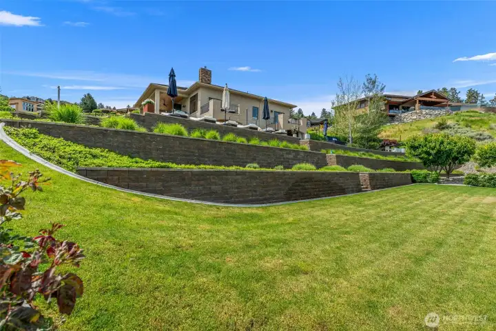 Exceptional outdoor design with tiered retaining walls and a big lush lawn for outdoor games