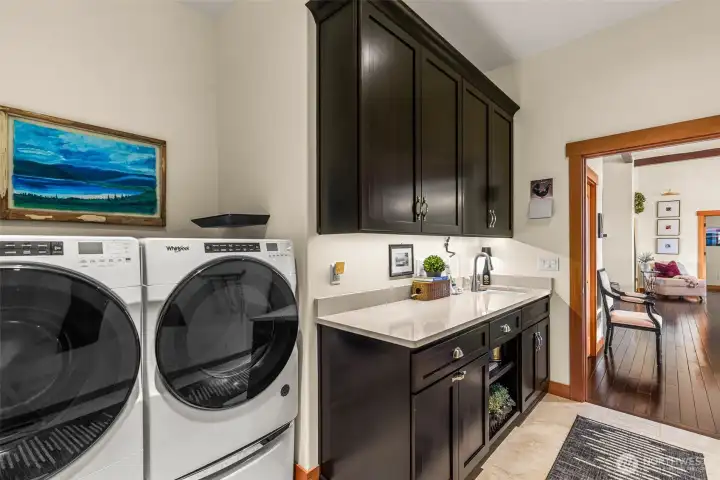Well-appointed laundry room with custom cabinetry, laundry sink and easy access to the main living areas