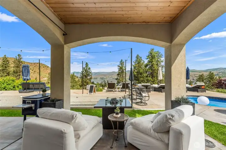 The perfect place to unwind—covered outdoor seating overlooks the pool, bocce ball court, lake, and surrounding mountains