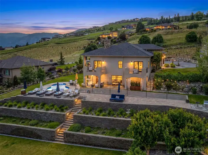This home is equally stunning at night, with glowing terraces, resort-style outdoor spaces, and a dramatic backdrop of vineyards and mountains.
