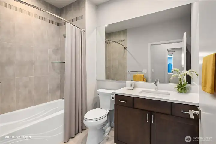 The combination of a spacious shower/tub and tasteful tilework enhances the bathroom’s appeal, making it a comfortable and inviting space.