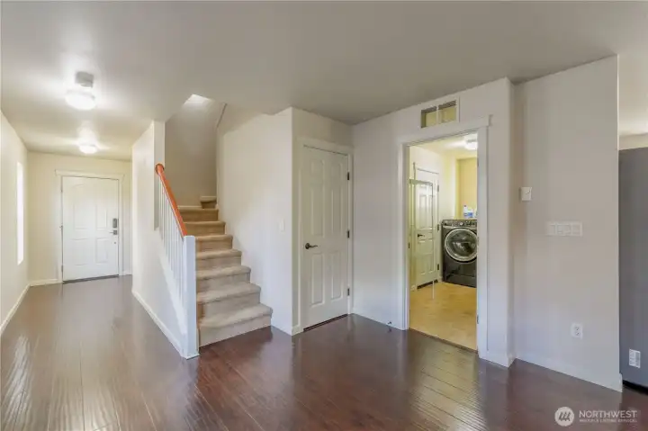 Front entryway. Front door to left in front, bathroom on the right of hallway. Staircase up. Coat closet to the right of stairway with laundry room and exit to garage