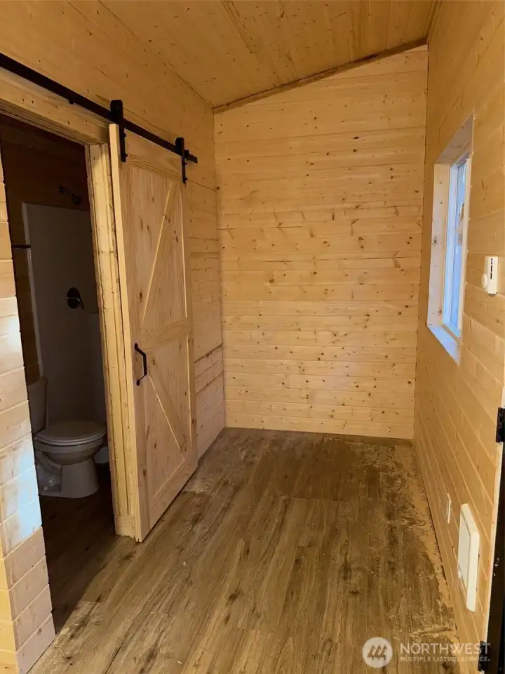 Barn door to bath with room for a bed.