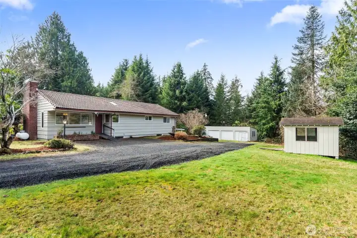 Property is over an acre and includes home, 3-bay detached garage with left-side garden storage, and a garden shed and dog house (on the left side)