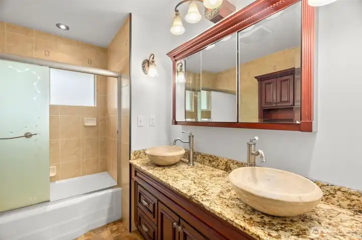 Main floor full bath w/ stone bowl sinks and storage in mirror medicine cabinet
