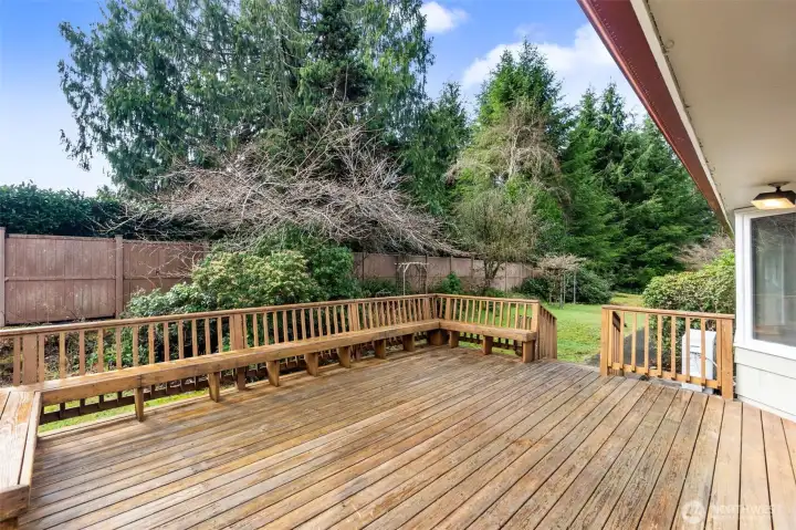 Large deck w/ built-in seating and right side view of backyard