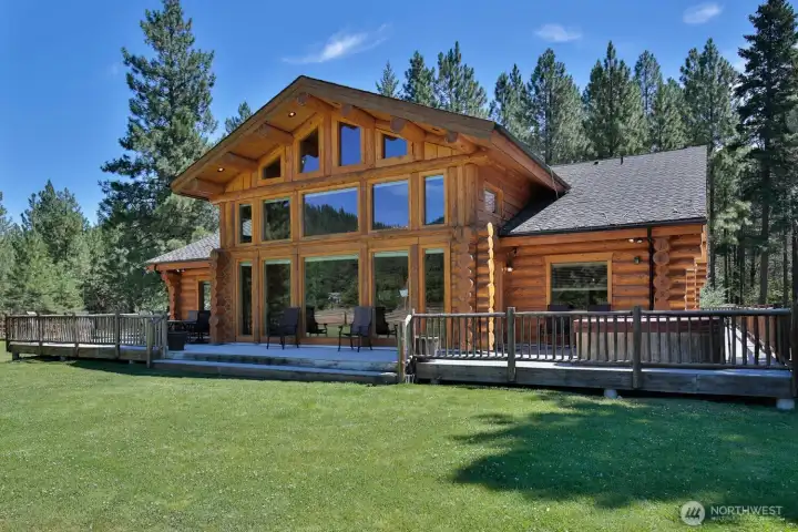 Showcasing a dramatic wall of glass, expansive entertaining deck, and serene pine setting—where indoor comfort meets outdoor living.