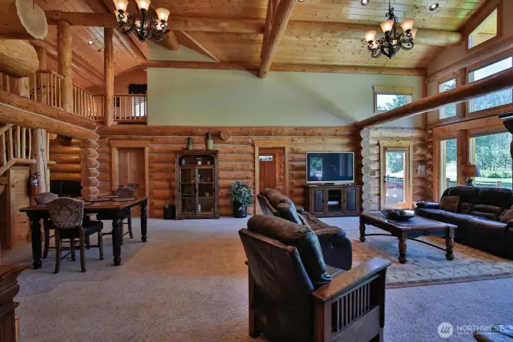 Grand open living space featuring exposed beams, lofted upper level, and multiple gathering areas for effortless entertaining.