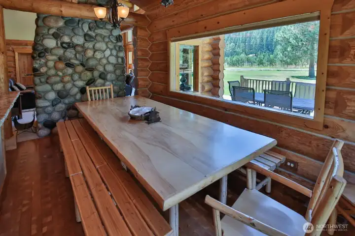 Spacious dining area with custom wood table and bench seating, positioned to capture views of the surrounding landscape.
