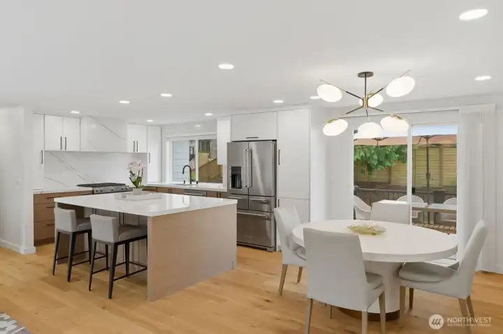 The designer kitchen impresses with premium finishes, including quartz countertops, a full-height quartz backsplash, a large center island, and quality Huntwood cabinetry extending to the ceiling for a custom, upscale aesthetic.