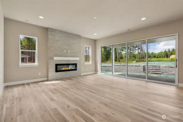 Spacious great room, highlighted by 10' ceilings, linear fireplace, and multip-panel sliding glass wall that opens to the spacious covered patio