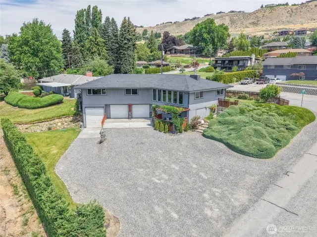 Expansive driveway with  access to a three-bay  garage, framed by a beautifully manicured lawn.