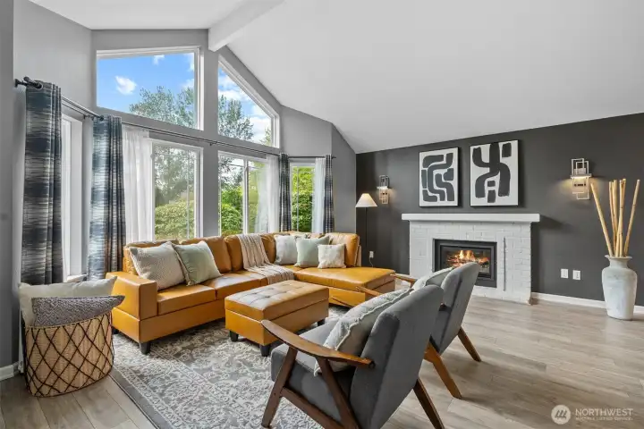 Spacious living room with a charming fireplace, offering a view of the landscaped front yard.