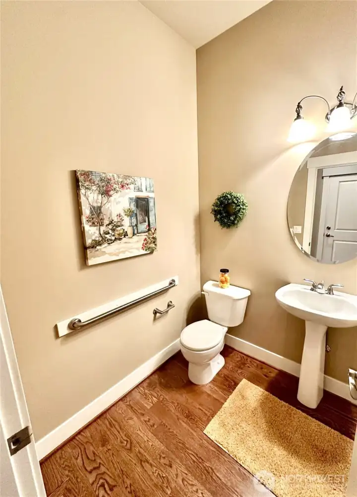 Powder room with hardwood floor and pedestal sink.