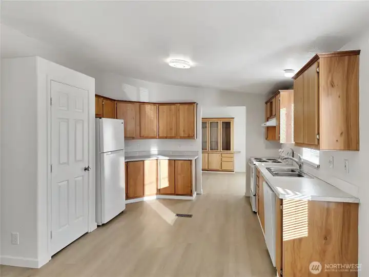 Inviting kitchen featuring warm oak cabinetry, new appliances, and a convenient step-in pantry. Plenty of counter space makes meal prep easy and enjoyable.