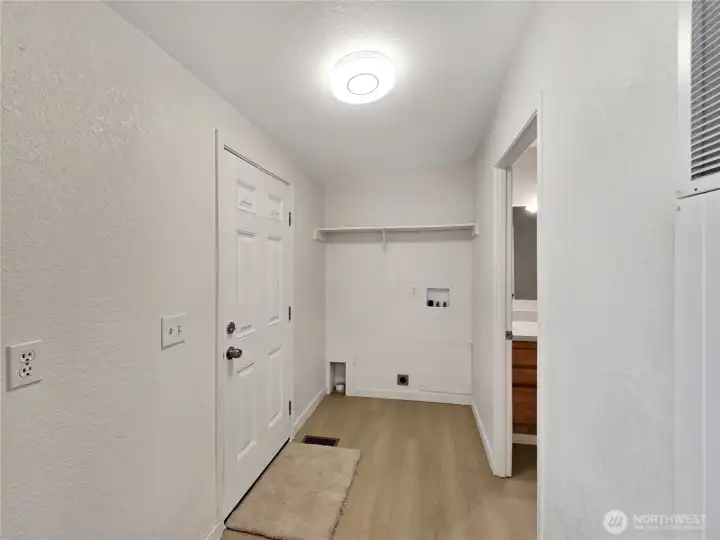 The laundry room has a built-in shelf for storage, convenient access to the bathroom, and direct entry from the porch—designed for everyday functionality.