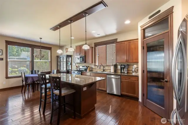 Kitchen at end of entry with walk in pantry next to refrigerator