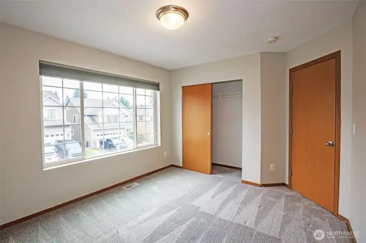 Spacious secondary bedroom with large window.