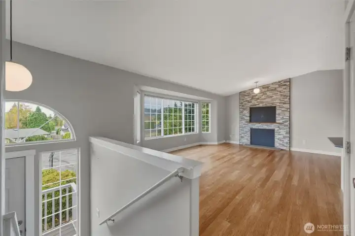 View of the entry, living room w/bay window and stone re-faced, wood-burning fireplace