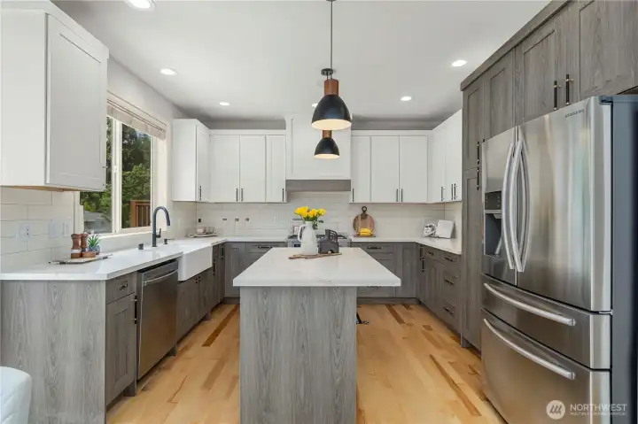 The chef’s kitchen features quartz countertops, new cabinetry, custom tile, and stainless steel appliances.