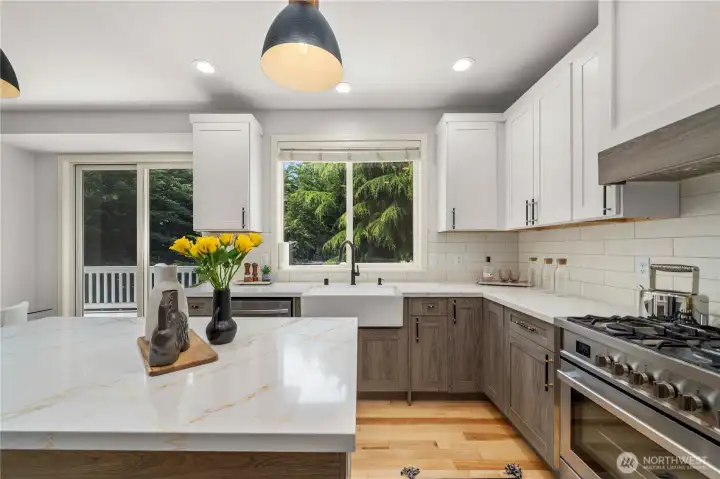 The chef’s kitchen features quartz countertops, new cabinetry, custom tile, and stainless steel appliances.