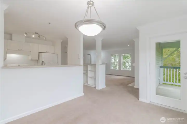 Dining area with open sightlines to the living room and kitchen. Door to the right leads to a private deck.