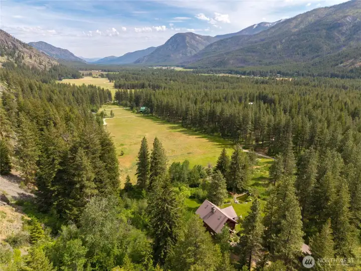 A rare aerial perspective showcasing the extraordinary privacy and scale of the property, with the custom lodge home nestled between forest, meadow, and surrounding mountain ridgelines. Located in the heart of Mazama with access to recreation, trails, and the natural beauty of the Methow Valley.