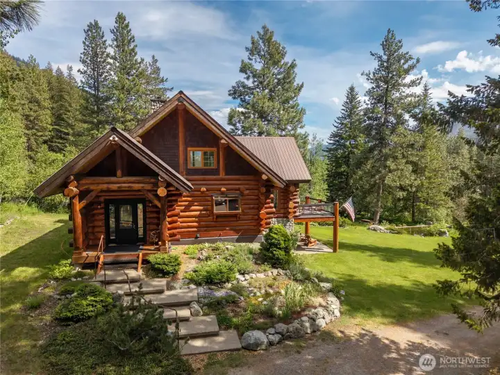 Authentic handcrafted log home surrounded by mature landscaping, open lawn, and towering pines in a peaceful Mazama mountain setting. Custom timber construction, dramatic rooflines, and expansive outdoor living spaces create a timeless lodge-style retreat in the heart of the Mazama.