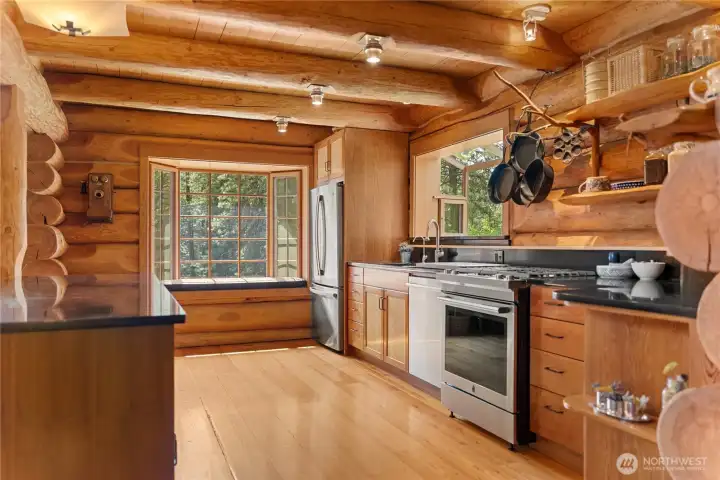 Warm and inviting kitchen with handcrafted cabinetry, wood ceilings, and natural finishes that reflect the timeless character of the lodge-style home. Open design connects seamlessly to the dining and gathering spaces.