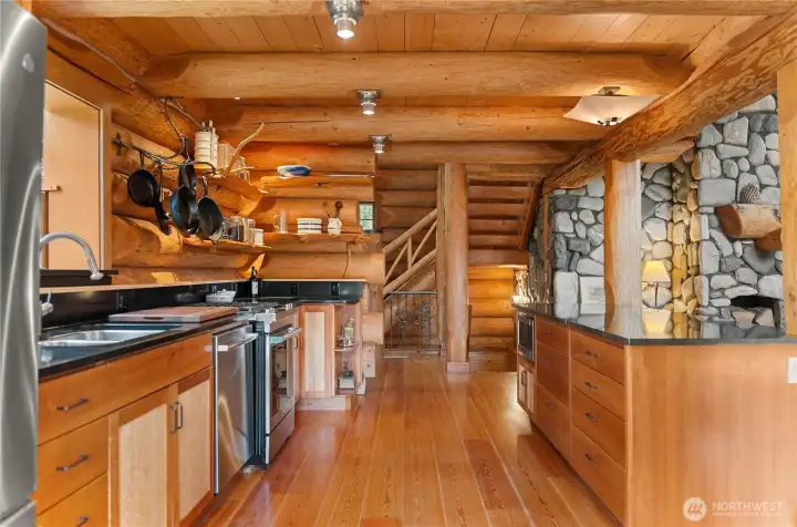Spacious lodge-style kitchen designed for gathering, featuring expansive counters, handcrafted wood finishes, and windows bringing natural light into the heart of the home. Open flow connects the kitchen, dining, and great room spaces for relaxed entertaining