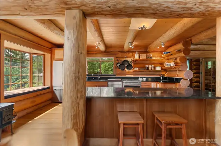 Kitchen with granite counters, artisan touches, and rich handcrafted wood finishes reflecting the timeless character. A built-in window seat and expansive bay window bring natural light and tranquil forest views into the heart of the gathering space.