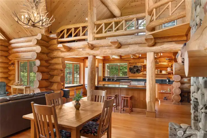Massive handcrafted logs, soaring timber ceilings, and an antler chandelier create a dramatic lodge-style gathering space rich with authentic Methow character. The surrounding loft overlooks the great room below, adding warmth, scale, and architectural presence throughout the home.