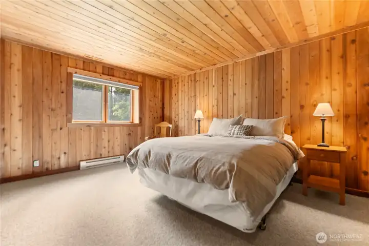 Spacious downstairs second bedroom with warm wood finishes, natural light, and a comfortable retreat feel—ideal for guests,