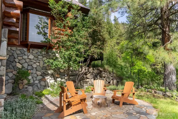 River rock walls, stone patio, and lovely natural landscaping create a warm and intimate outdoor setting tucked among the trees—perfect for quiet evenings, stargazing, or relaxing fireside, entertaining friends, and relaxing in the peaceful mountain surrounding.