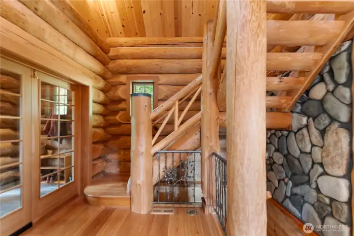 Welcoming main entry with dramatic river rock accents and custom wrought iron railing handcrafted by a local artisan, leading upstairs to the loft area and downstairs to the expansive lower level living and recreation spaces.