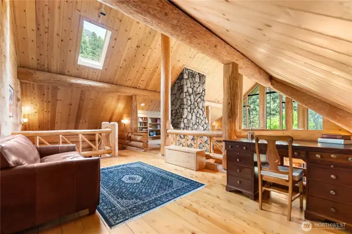 Expansive upper-level retreat featuring hand-scribed log accents, soaring wood ceilings, skylights, and dramatic river rock chimney details. This flexible loft space is ideal as a luxury bunk room, executive home office, study, reading lounge, creative studio, yoga or wellness space, media/game room, or peaceful retreat area overlooking the great room and surrounding mountain landscape.