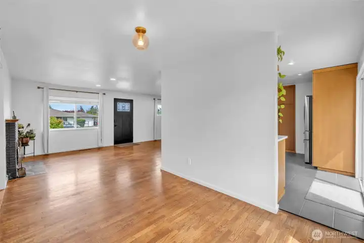 Photo from perspective dining area, shows entrance to kitchen, den, and front door of the home.
