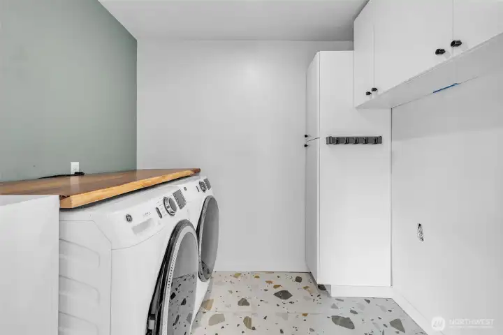 Laundry Room- Fun speckled tile. Fitted wood countertop for washer and dryer, and built in shelving. Enclosed with a sliding door.