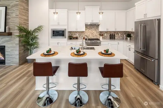 Gourmet kitchen with white shaker cabinets, quartz countertops, fully height herringbone pattern backsplash and upgraded Kitchenaid appliances