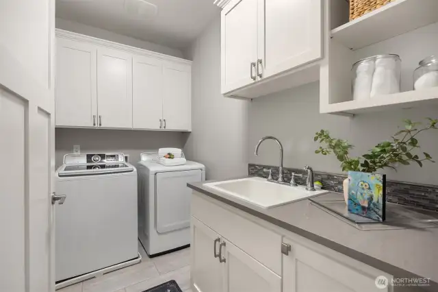 Large spacious laundry room with a sink, folding counter, and lots of storage.